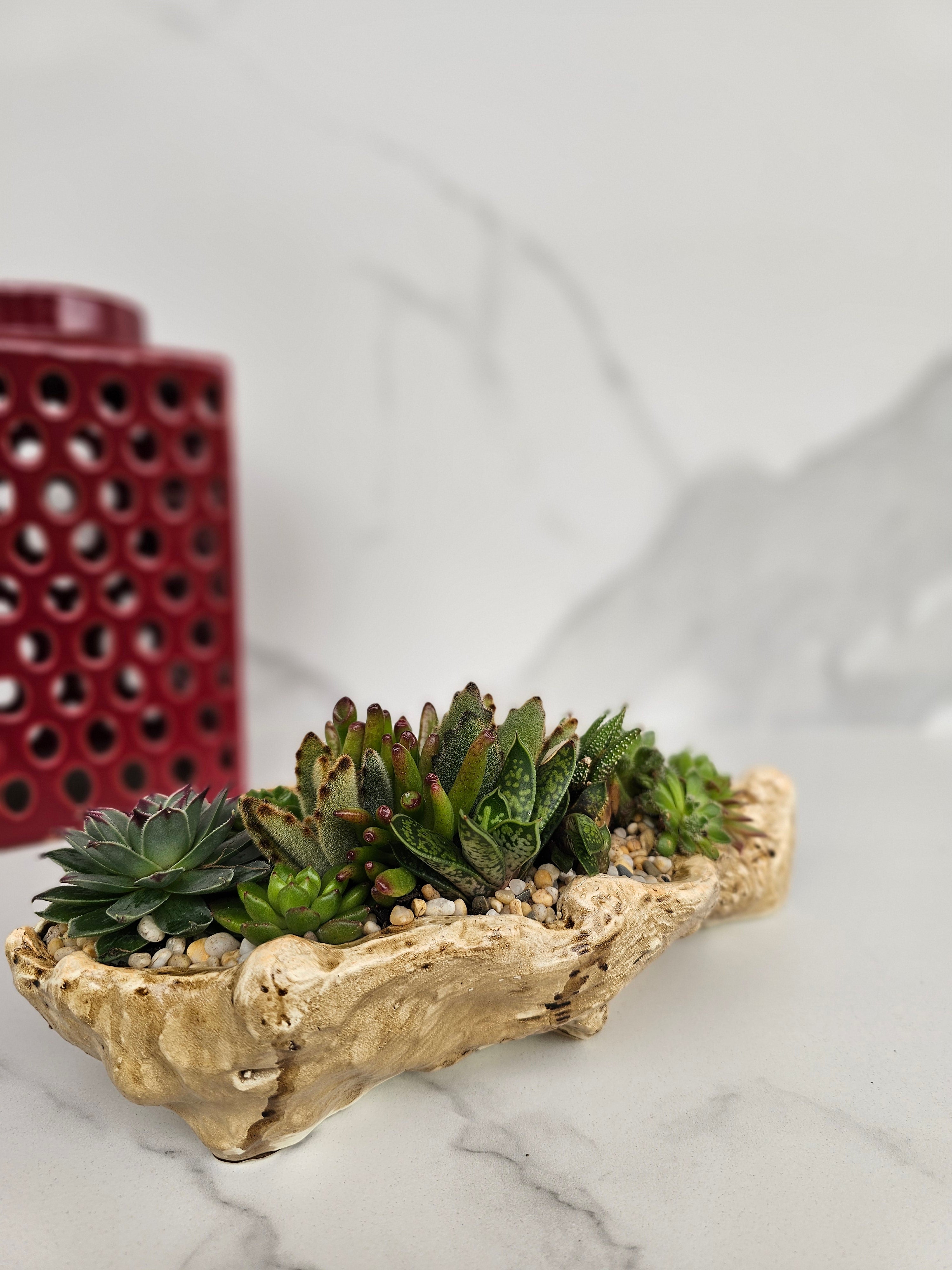 Decorative wall piece with greenery and beige stone against a marble background