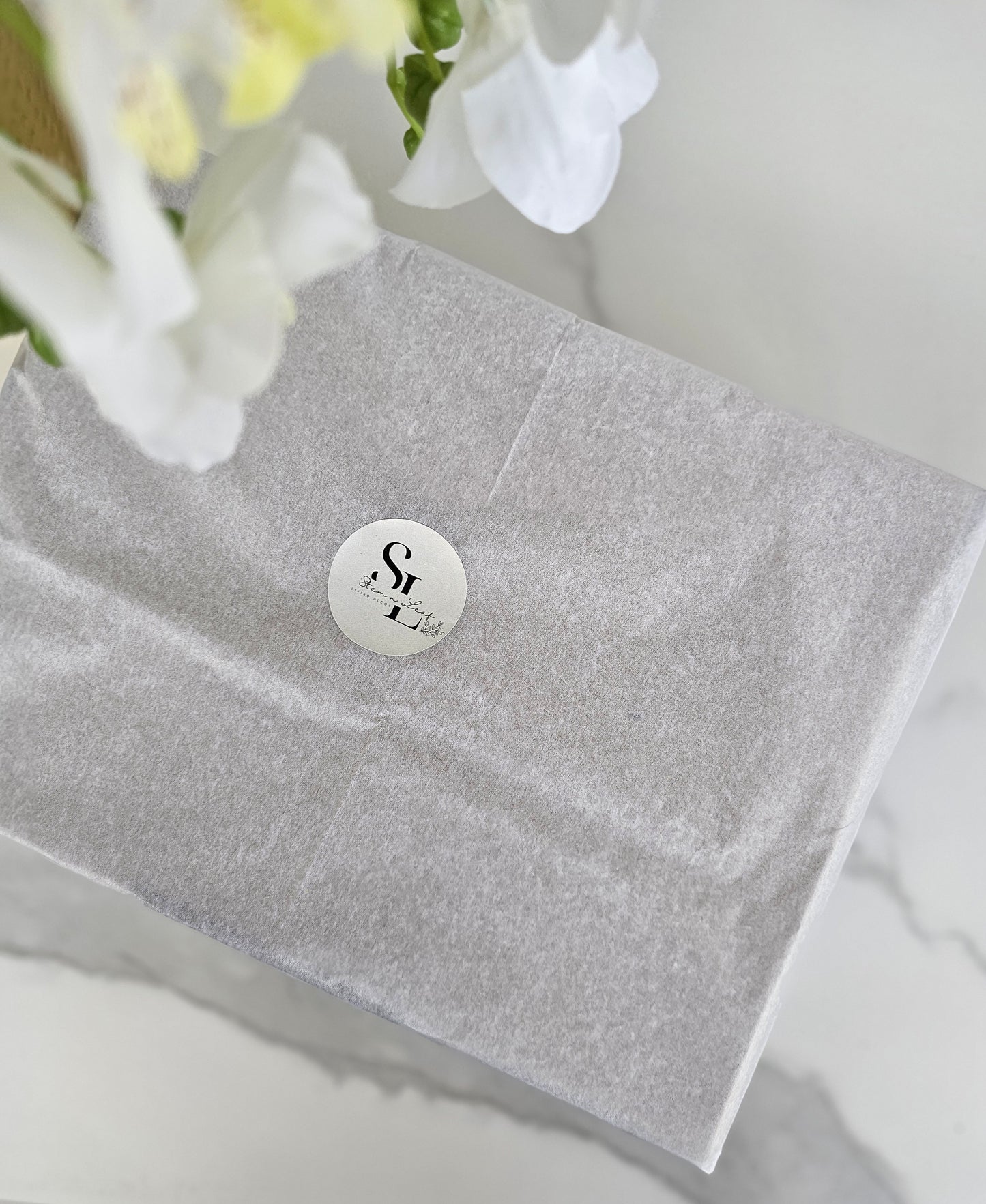 Sleek modern box with a round label featuring Stem n Leaf on a white surface with flowers.