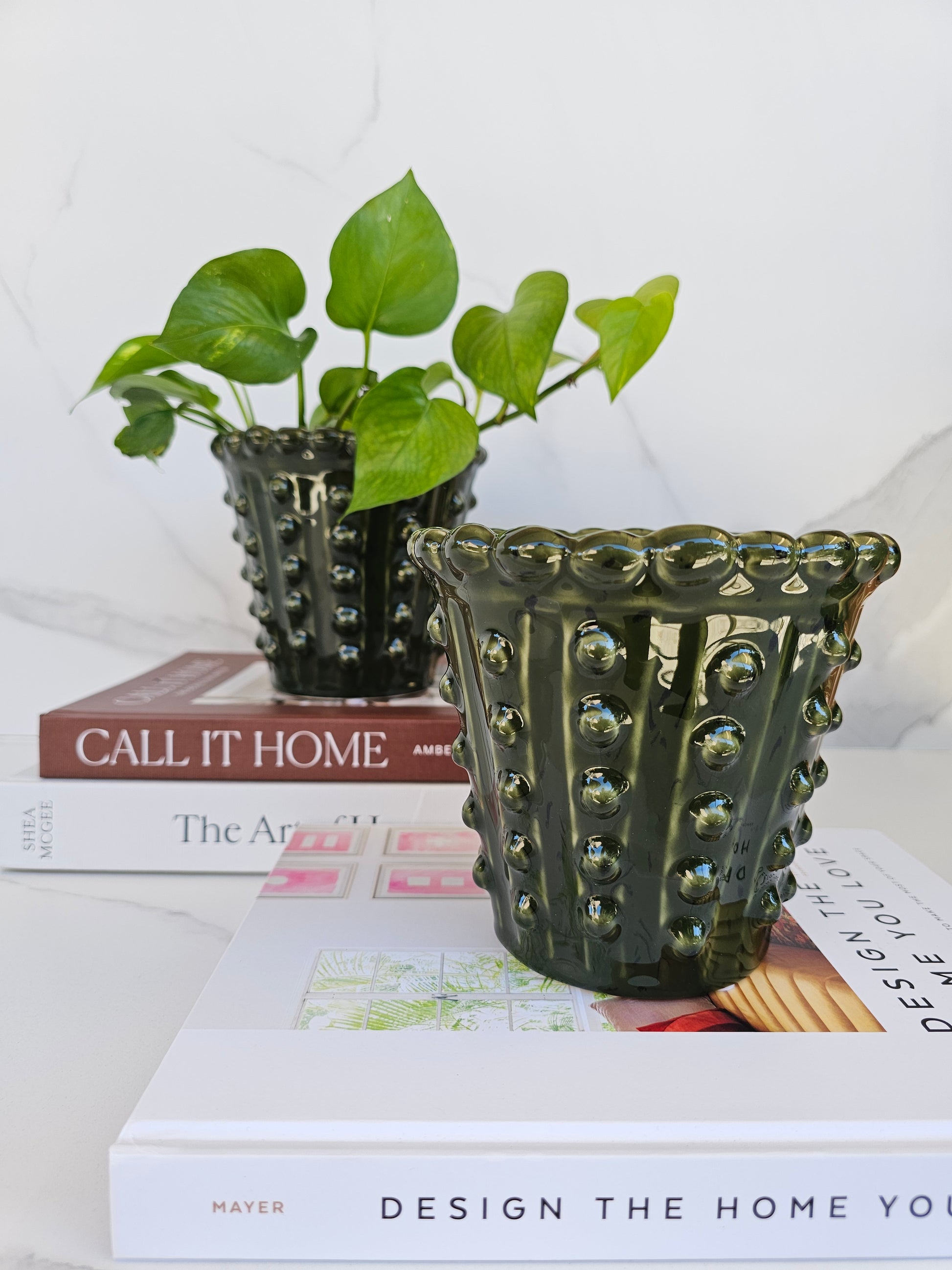 Deep green ceramic planter displayed on a shelf in a modern home interior.