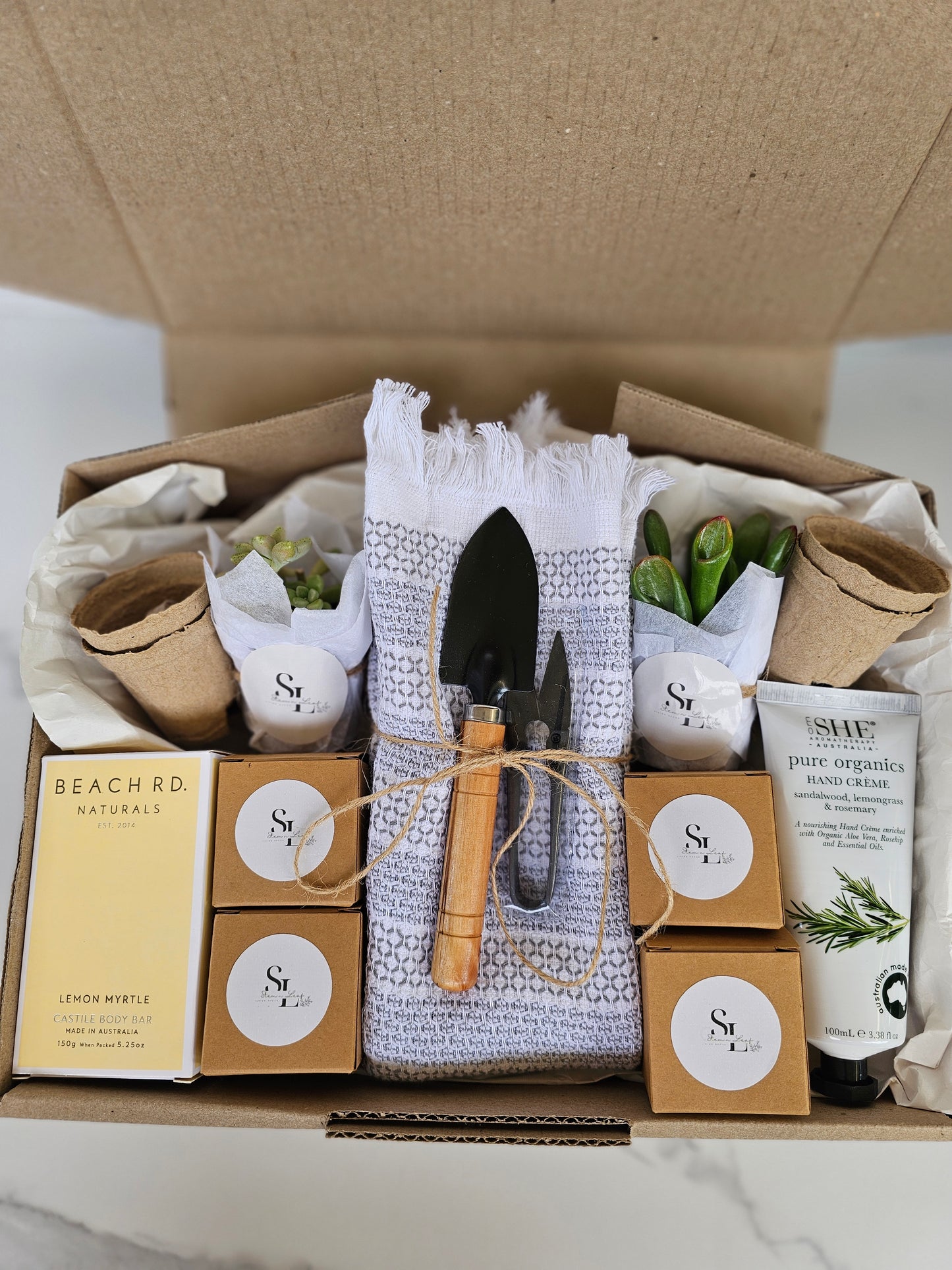 Box containing gardening-themed items including trowels, plants, and boxes with labels.