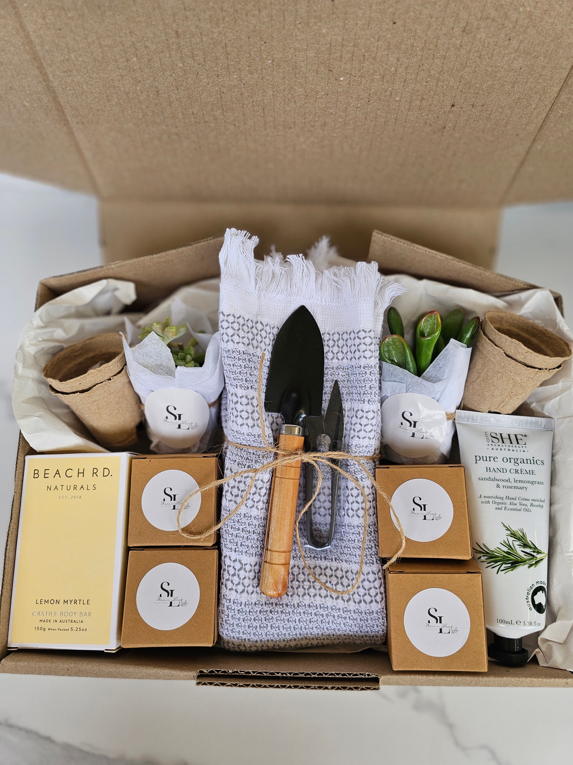 Box containing gardening-themed items including trowels, plants, and boxes with labels.