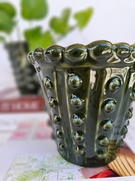 Close-up of the raised hobnail detailing on a deep green ceramic planter.