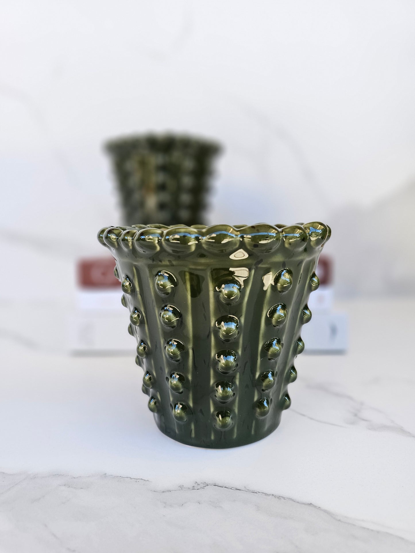 Side view of a glossy deep green ceramic hobnail planter for indoor plants.